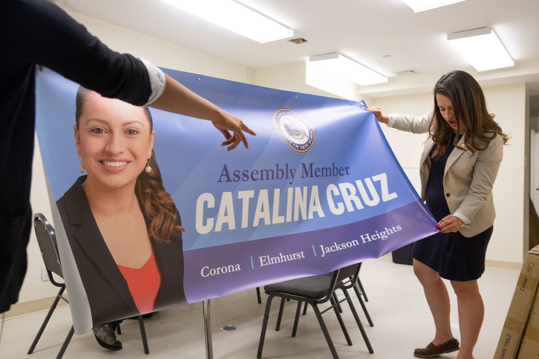 New York Assemblywoman Catalina Cruz examining a decorative banner at her office in Corona, Queens. Although now a citizen, Ms. Cruz grew up undocumented. She said this has informed many of her policy decisions.